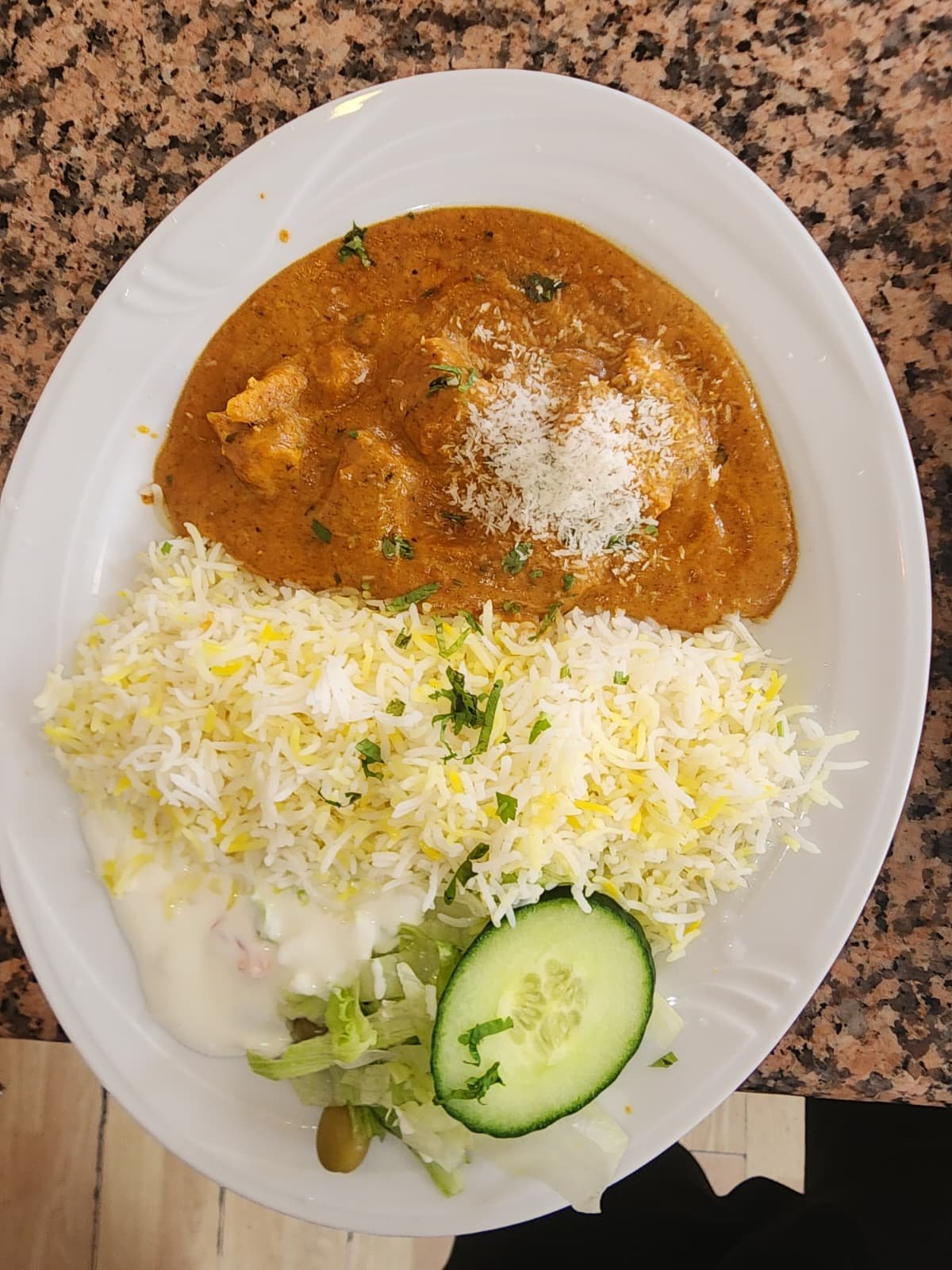 Curry especiado servido con arroz basmati, ensalada y salsa de yogur