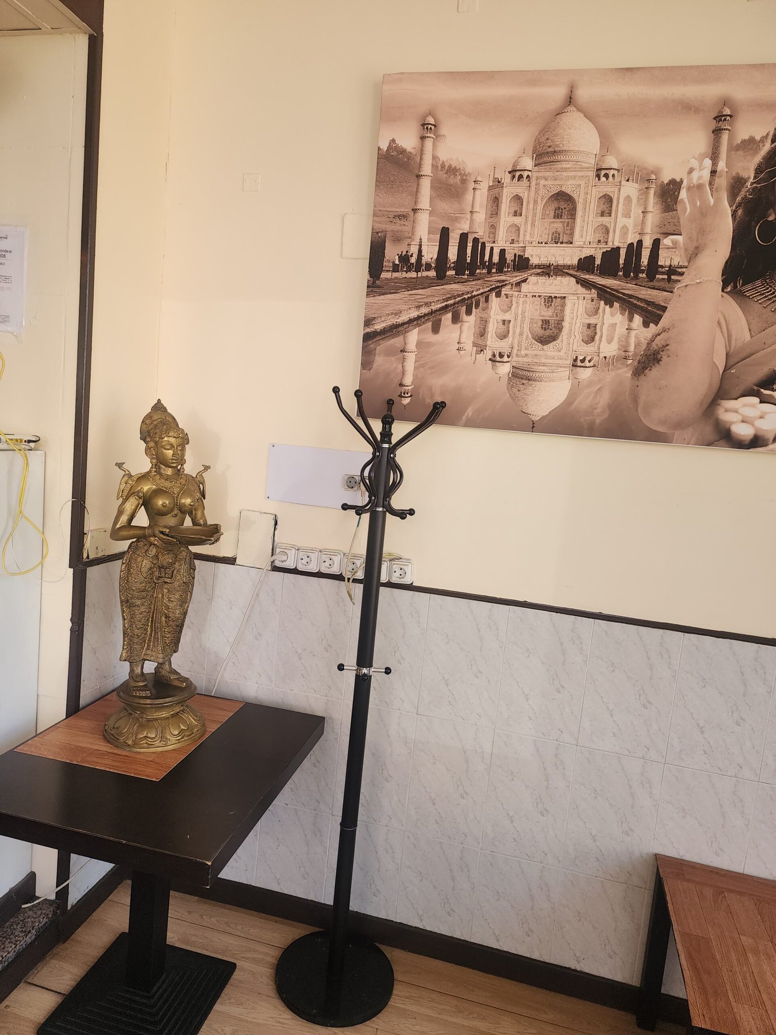 Rincón del restaurante con figura dorada y cuadro del Taj Mahal